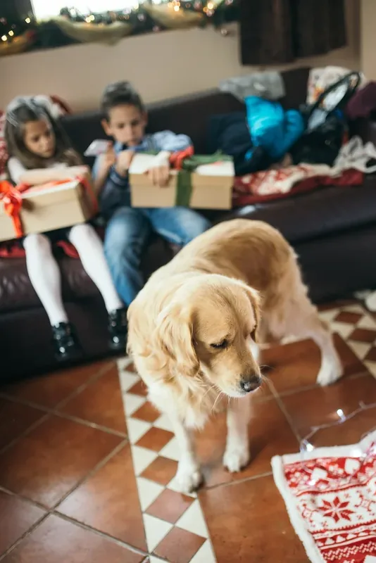 In a festive living room, a golden retriever stands nearby as two children unwrap Christmas presents, filled with joy and anticipation. The warm atmosphere features decorations.